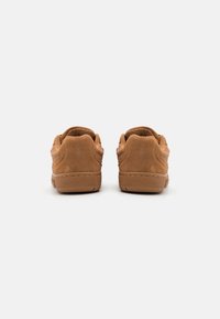Braune Wildledersneaker mit strukturiertem Obermaterial, abgerundetem Absatz und Gummisohlen, die entlang der Kanten mit einer Naht versehen sind.
