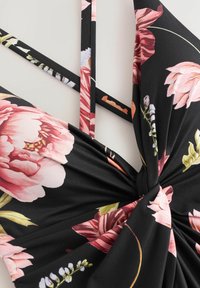 Costume da bagno floreale nero con motivi di fiori rosa e verdi, design del collo intrecciato e spalline sottili e regolabili. Tessuto morbido.