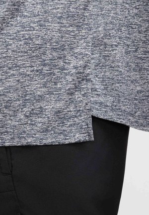 Graues meliertes Gewebe mit abgerundetem Saum und lockerem Schnitt, kombiniert mit schwarzem Material darunter. Glatte Textur, modernes Design.