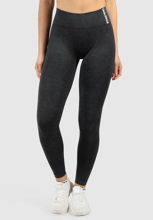 Leggings neri realizzati in materiale elastico. Vita alta con dettagli a coste. Presenta un piccolo logo sul lato. Texture liscia.