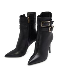 Bottes noires en cuir à talons hauts, chevilles, bouts pointus, fermetures éclair latérales et doubles sangles décoratives avec boucles dorées.