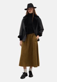 Black leather jacket with faux fur collar, fitted turtleneck, mustard long skirt, black shoes, and white ribbed socks. Black hat as an accent.