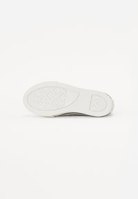 Witte rubberen sneakerzool met een gestructureerd grippatroon en logo-details. Glad materiaal met afgeronde randen en een flexibele vormgeving.