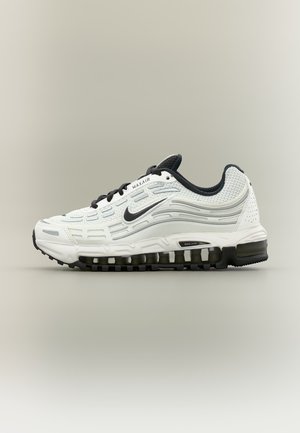 Chaussure de course Nike Max Air blanche et noire avec amorti visible à air et tige en mesh, vue de côté sur un fond neutre.
