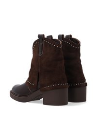 Ciemnobrązowe botki za kostkę z masywnymi obcasami, zamszowa cholewka, skórzane czubki i srebrne ćwieki wzdłuż krawędzi i boków.