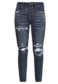 Vaqueros de tiro alto, ajustados, en denim azul oscuro, con detalles desgatados y múltiples cierres de botones en la cintura.