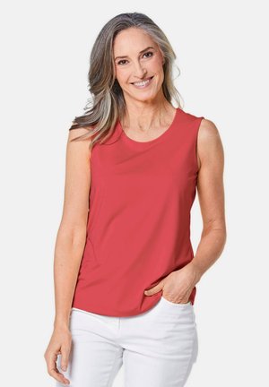 Haut sans manches rouge en tissu doux et lisse avec un col rond. Associé à un pantalon blanc, présentant une coupe décontractée et un design minimaliste.
