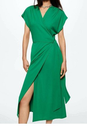 Donna che indossa un vestito avvolgente verde con scollatura a V, maniche a cappuccio, uno spacco laterale e una cintura in vita, abbinato a una collana in argento a catena.