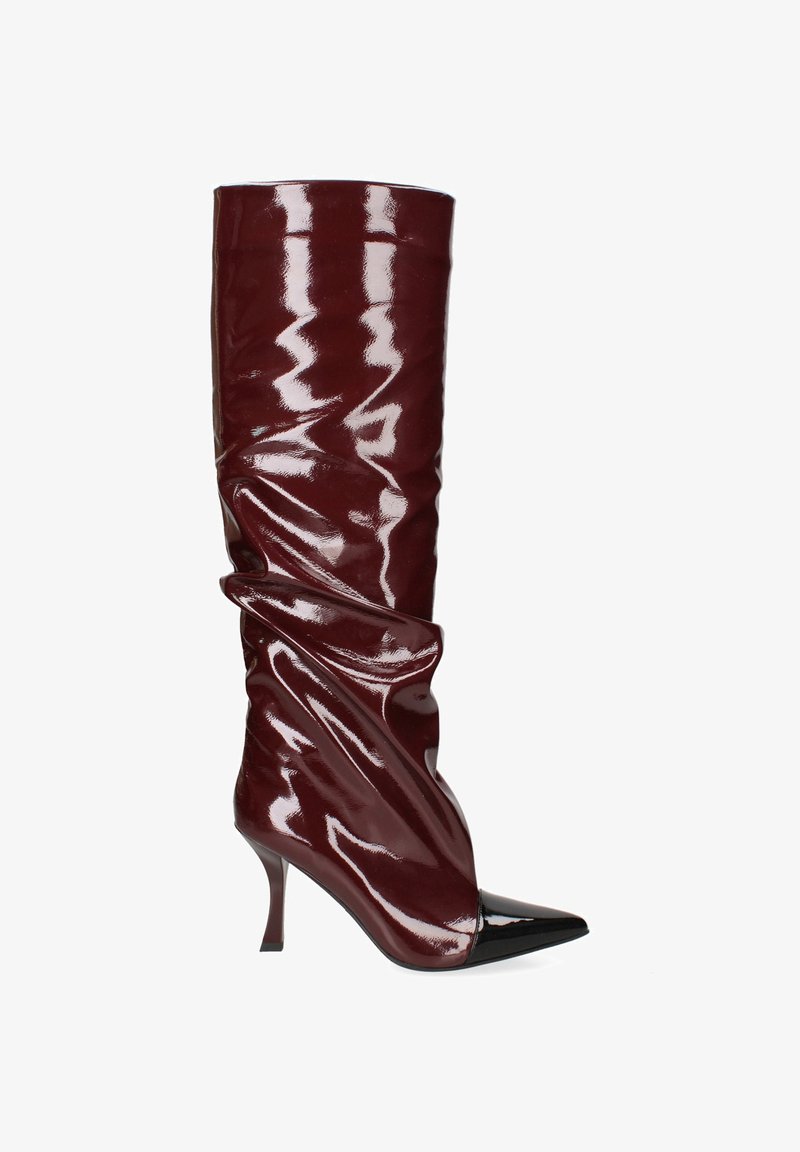 Bordeauxkleurige laars tot de knie van glanzend materiaal, met een slouch-ontwerp en een spitse zwarte neus. De stilettohak voegt hoogte toe.