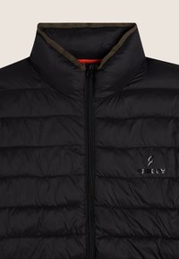 Chaleco acolchado negro con cuello alto, cierre de cremallera, costuras horizontales y detalle sutil de logo en el pecho. Acento marrón a lo largo del cuello.