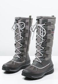 Botas de invierno grises con parte superior acolchada, sistema de cordones, cierre con cremallera, suela de goma texturizada y acentos en contraste en gris y blanco.
