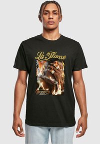Melna kokvilnas T-kreklu ar grafisku attēlu, kurā redzama roka ar gredzeniem pret uguns fonu; teksta "La Flame" zeltā virs un logotips apakšā.