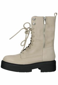Beige enkellaarsjes van soepel leer met een stevige zwarte zool, uitgerust met veters aan de voorkant, een zijrits en zilverkleurige hardware-accenten.