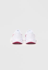 Witte sportschoenen met een gestructureerde bovenkant, roze accenten op de hiel en zijkanten, en een robuuste rubberen zool met een grippatroon.