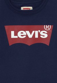 Indumento blu navy con logo rosso Levi's sul petto, caratterizzato da testo bianco in grassetto e un simbolo di marchio registrato.