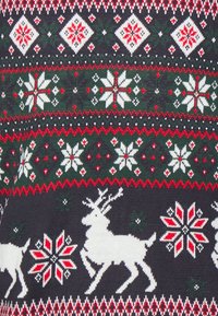 Stickad tröja med en mörk bakgrund och vita renar samt snöflingemönster i röd och grön, framhävt av geometriska motiv.