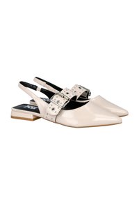 Zapatos slingback beige con punta afilada, acabado brillante y hebilla decorativa con tachuelas en la correa. Diseño de tacón bajo y bloque.