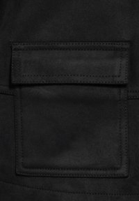 Svart tyg med en mjuk textur har en rektangulär ficka med stickade kanter. Ytan verkar mjuk och matt.