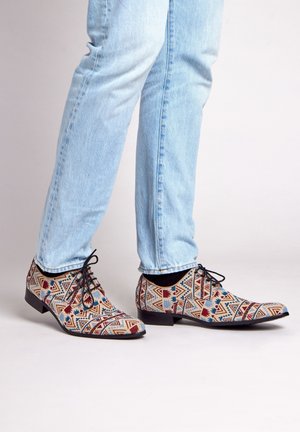 Patroon geklede schoenen met een geometrisch ontwerp in blauwe, rode en beige tinten. De schoenen hebben een platte zool en vetersluiting.