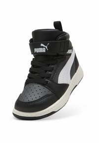 Zapatilla negra de media caña con upper de cuero texturizado, acentos blancos, detalles perforados y una correa con el logo de Puma.