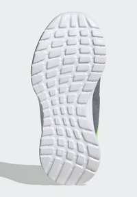 Semelle de chaussure avec une surface en caoutchouc blanc texturé, présentant un motif en grille. Accentuée par un panneau latéral gris avec une touche de vert fluo.