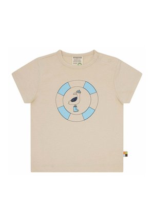 Hellbeige T-Shirt mit kurzen Ärmeln, das ein rundes blau-weißes Logo mit einem Pelikan in Hut und Stiefeln zeigt, aus weicher Baumwolle gefertigt.