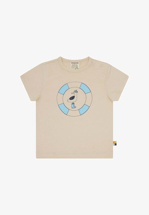 Hellbeige T-Shirt mit kurzen Ärmeln, das ein rundes blau-weißes Logo mit einem Pelikan in Hut und Stiefeln zeigt, aus weicher Baumwolle gefertigt.