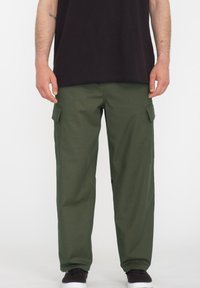 Cargo pants in donkergroene katoenstof, met twee zijzakken, een relaxte pasvorm en een over het algemeen gladde textuur. Gecombineerd met een zwart shirt.