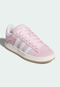 Baskets en daim rose avec des bandes en cuir blanc, des lacets plats blancs, une languette matelassée et une semelle en caoutchouc gomme ; logo sur la languette.