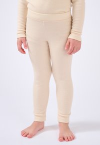 Leggings a coste beige realizzati in tessuto morbido con vita elastica e polsini alla caviglia, progettati per il comfort e la facilità di movimento.