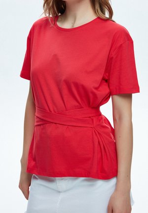 Rød kortærmet T-shirt lavet af blødt jersey stof, med en tætsiddende talje og en bundet bælte samt indsamlede detaljer på siderne.