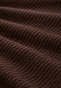 Brauner Strickstoff mit einem strukturierten, wellenförmigen Muster. Das Material wirkt weich und dicht, ideal für Wärme und Komfort.