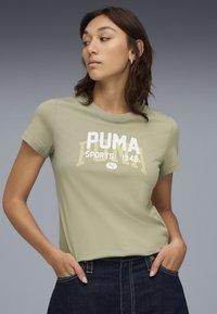 Camiseta verde de manga corta con cuello redondo, que presenta un gráfico impreso en blanco y amarillo que dice "PUMA SPORTS 1948" en la parte frontal.