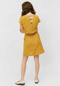Vestido amarillo de lunares con mangas cortas y cintura ajustable. Presenta cortes en la espalda y un ajuste relajado. Tela suave y ligera.