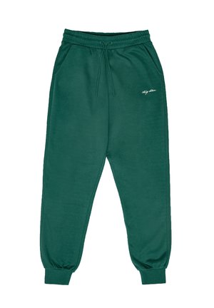 Zaļas kokvilnas sporta bikses ar elastīgu jostu, sānu kabatām un ribotām piedurknēm. Uz kreisās augšstilba ir neliels balts logotips.