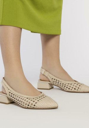 Chaussures slingback tissées beiges avec un bout pointu et des côtés ouverts, présentant un petit talon bloc et un motif découpé complexe.