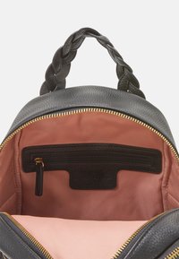 Zwarte leren rugzak met een gevlochten handvat bovenaan, gouden rits en een roze stoffen interieur met een ritsvak en logodetail.