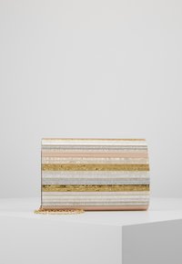 Clutchväska med horisontella ränder i guld, silverglitter, pärlvitt och ljusrosa, liggande på vit yta med en del av en guldkedja synlig.