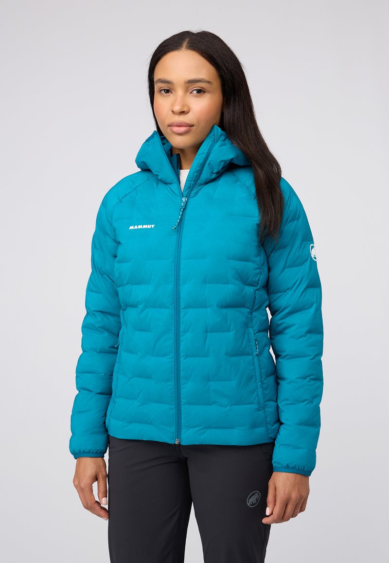 Teal puffjacka med hög krage, dragkedja och logotyp. Har en kviltad design och elastiska ärmslut. Lämplig för kallt väder.