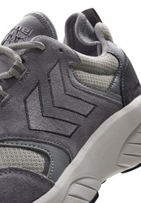 Grå sportskor med övre i mocka, mesh detaljer och gummisula. Distinkt chevron-mönster på sidan.