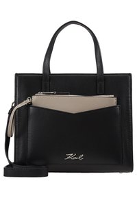 Sac à main en cuir noir avec doubles poignées, poche avant en noir et beige, logo "Karl" argenté et bandoulière amovible.