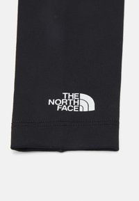 Mustad mustad retuusid venivast kangast, millel on suletud tekstuur ja sobiv disain, ning hemist lähedal on valge "THE NORTH FACE" logo.