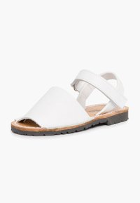 Sandali bianchi con design a intaglio, tomaia in pelle, cinturino regolabile e suola marrone. Caratterizzati da una texture liscia e punta aperta.