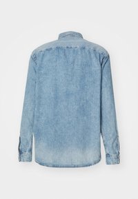 Light blue denim shirt with long sleeves, button-down collar, and a slightly faded texture. Features a straight cut and buttoned cuffs.