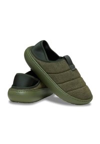 Scarpe slip-on verde oliva con tomaia in tessuto testurizzato, dettagli imbottiti e suole in gomma. Presentano una soffice fodera traspirante e un linguetta per l'estrazione.