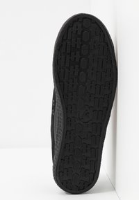 Black rubber shoe sole with textured grip pattern, featuring side buttons and a smooth upper edge. Size indicator visible as "37."