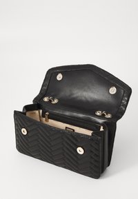 Schwarze, gesteppte Leder-Geldbörse mit umklappbarem Deckel, ausgestattet mit goldfarbenen Hardware, zwei Druckknopfschließen und einem Reißverschluss-Innenfach.