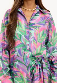 Kleurrijk overhemd met knopen, volledig met een tropisch bladerenpatroon in groen, roze en paars. Glad geweven stof met zakken en een geknoopte detail in de taille.
