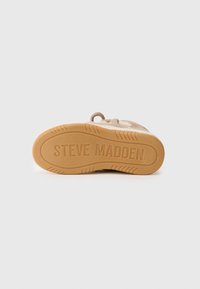 Béžové tenisky s textúrovaným zvrškom, okrúhlou špičkou a gumovou podrážkou s vyrazeným nápisom "STEVE MADDEN". Šnúrková detailácia blízko otvoru.