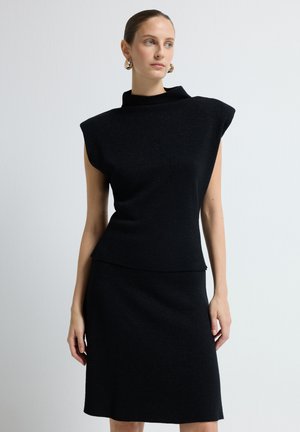 Ensemble de robe en tricot noir avec un col montant, de courtes manches en forme de cape et une silhouette ajustée. Texture lisse avec un éclat subtil.
